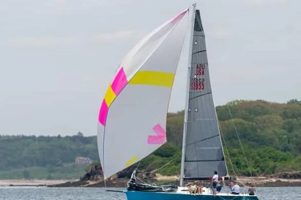 Slide: The Image of 2007 Hallett 33 sailboat with colorful spinnaker sailing near a forested shoreline. - 4
