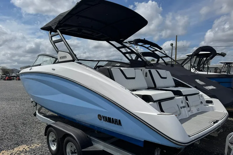 Slide: The Image of 2026 Yamaha Boats 252SD in blue and white on a trailer, under a cloudy sky. - 2