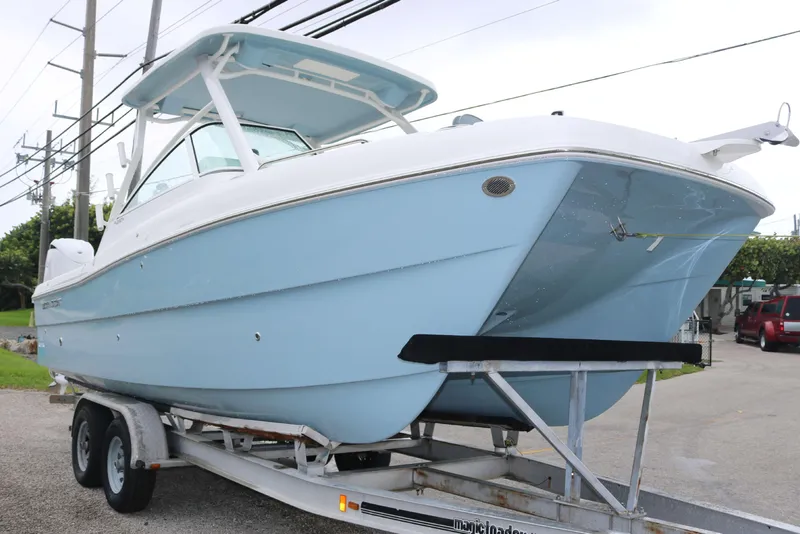 Slide: The Image of 2026 World Cat 230 DC boat on trailer, light blue hull, parked outdoors. - 2