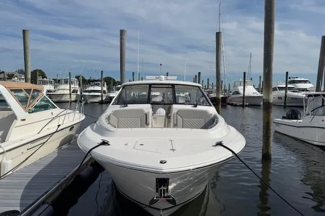 Slide: The Image of 2025 Pursuit DC 365 Dual Console boat docked in a marina, surrounded by other vessels. - 1