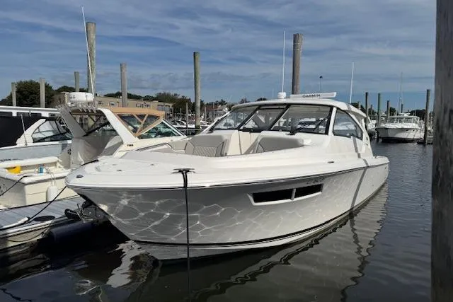 Slide: The Image of 2025 Pursuit DC 365 Dual Console boat docked in marina under clear sky. - 2