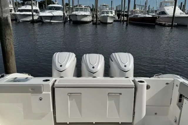 Slide: The Image of 2025 Pursuit DC 365 Dual Console boat with triple engines docked at marina. - 28