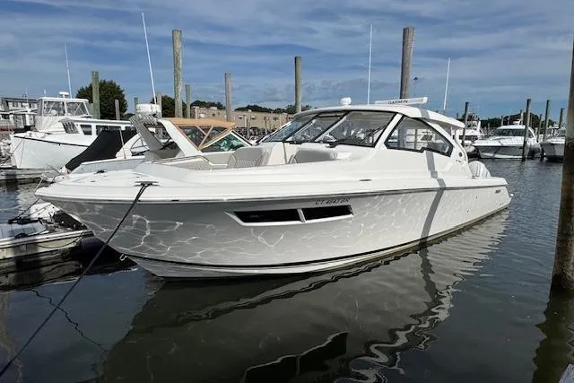 Slide: The Image of 2025 Pursuit DC 365 Dual Console boat docked in a marina under a clear sky. - 3