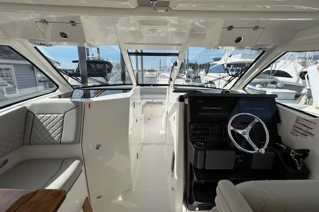 Slide: The Image of 2025 Pursuit DC 365 Dual Console interior with helm, seating, and marina view. - 30