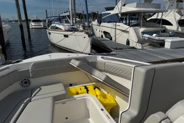 Slide: The Image of 2025 Pursuit DC 365 Dual Console boat interior at marina, showcasing seating and storage. - 36