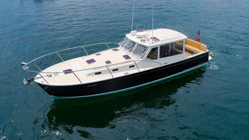 Slide: The Image of 2012 MJM 40z Downeast boat cruising on calm water, featuring sleek design and American flag. - 2