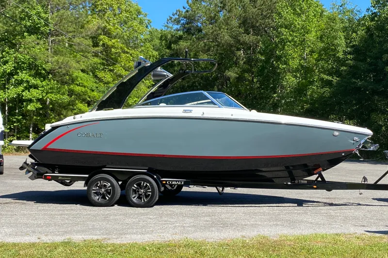 The Image of 2020 Cobalt R5 boat on trailer, parked outdoors with lush green trees. - 1