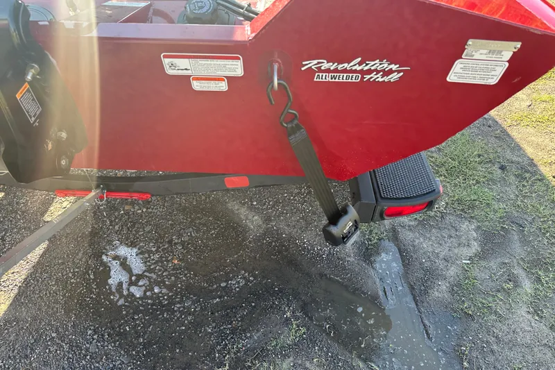 Slide: The Image of 2024 Tracker Pro Team 195 TXW Tournament Edition boat, red hull, parked on gravel. - 13