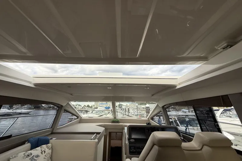 Slide: The Image of Interior view of 2018 Sea Ray Sundancer 460 yacht with open sunroof and marina backdrop. - 8