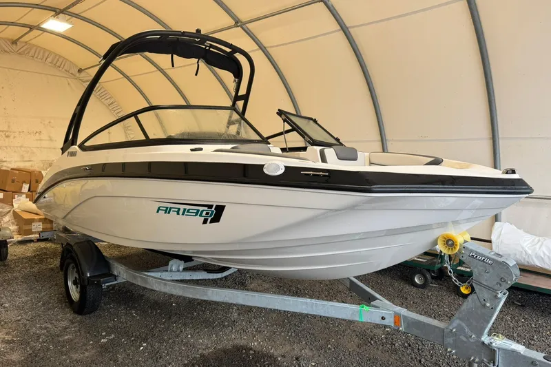 The Image of 2026 Yamaha Boats AR190 in storage, sleek design, on trailer, under shelter. - 0