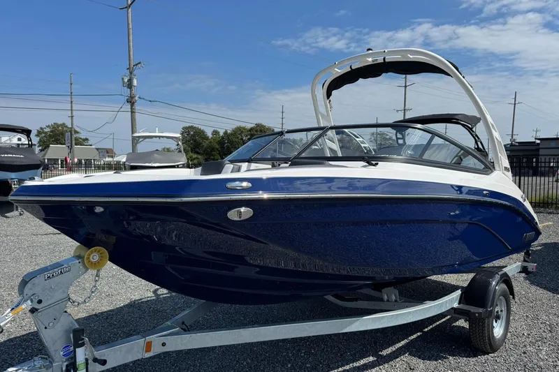 The Image of 2026 Yamaha Boats 195S on trailer, sleek blue and white design, parked outdoors. - 0