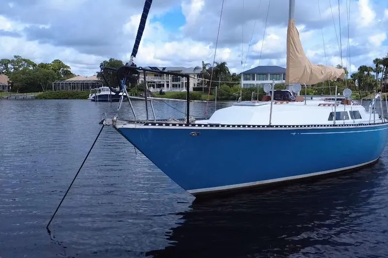 Slide: The Image of 1980 C&C Landfall 38 sailboat anchored on calm water, with scenic background. - 20