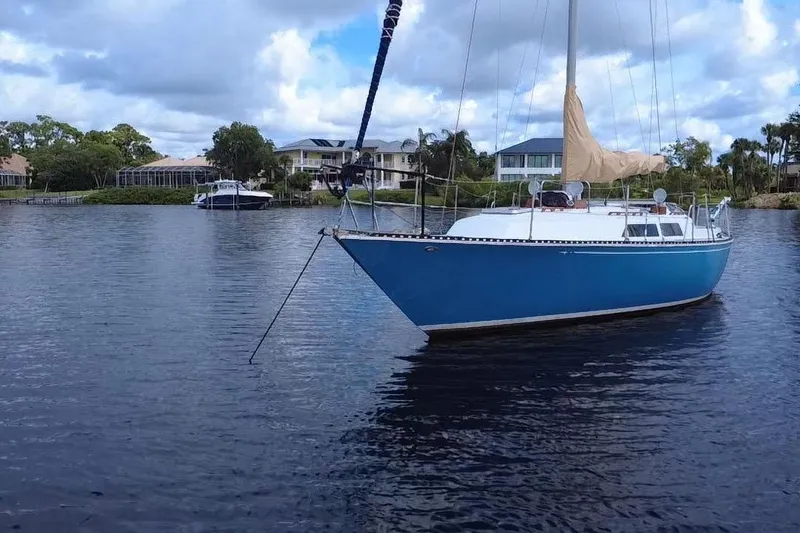 Slide: The Image of 1980 C&C Landfall 38 sailboat anchored on calm water with scenic background. - 21