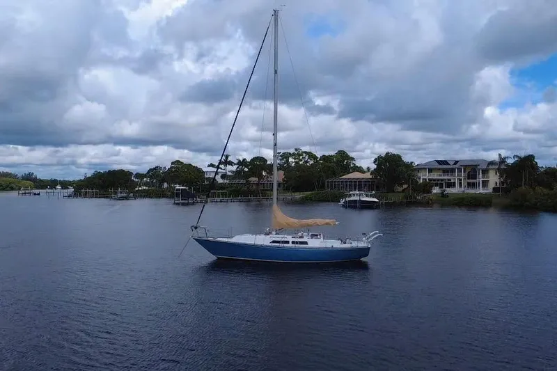 Slide: The Image of 1980 C&C Landfall 38 sailboat on calm water, cloudy sky, waterfront homes in background. - 26