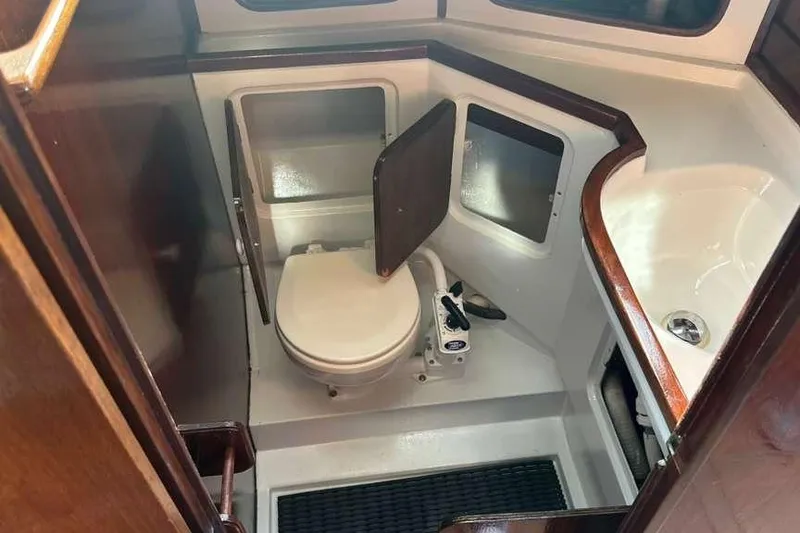 Slide: The Image of 1980 C&C Landfall 38 yacht bathroom with toilet and sink, featuring wood accents. - 32