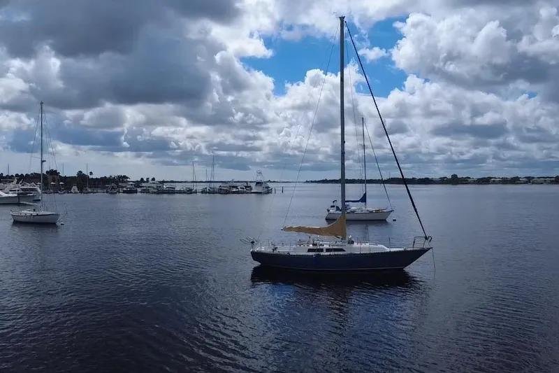 Slide: The Image of Sailboats anchored in a calm harbor under a cloudy sky, featuring a 1980 C&C Landfall 38. - 39