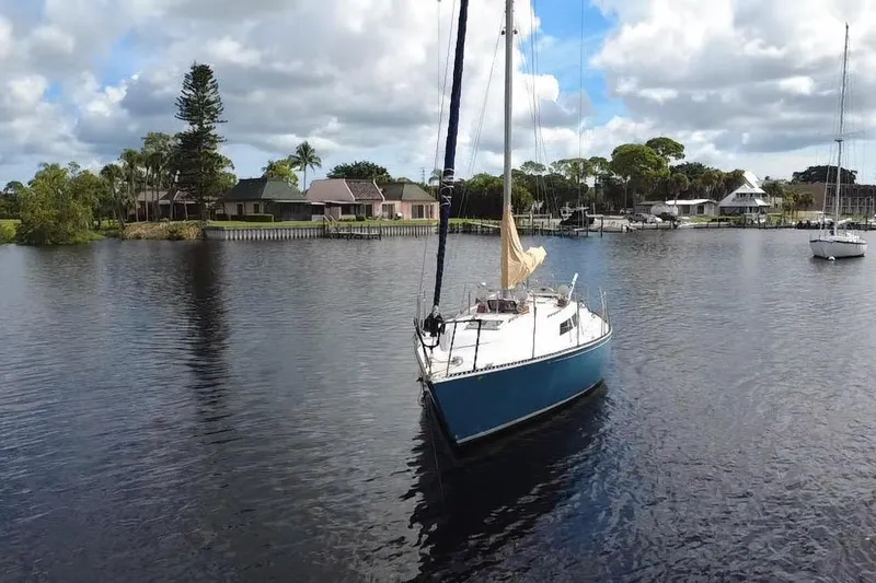 Slide: The Image of 1980 C&C Landfall 38 sailboat on calm water near residential area, under cloudy sky. - 45
