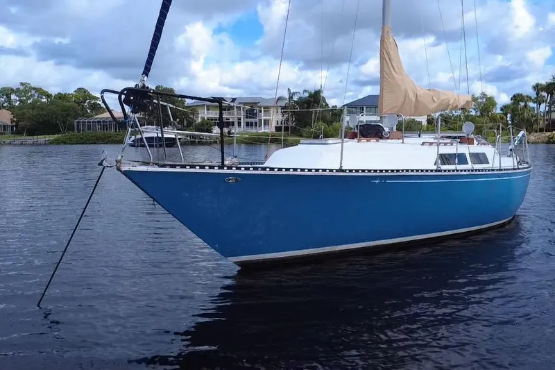 Slide: The Image of 1980 C&C Landfall 38 sailboat with blue hull anchored on calm water. - 49