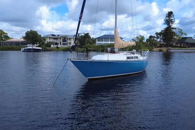 Slide: The Image of 1980 C&C Landfall 38 sailboat on calm water, with houses and trees in the background. - 55