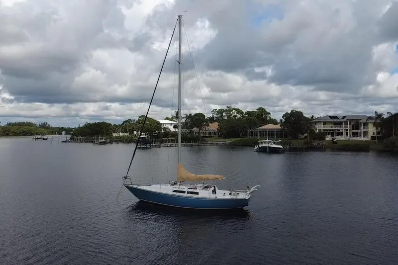 Slide: The Image of 1980 C&C Landfall 38 sailboat anchored on a calm river with cloudy skies. - 58