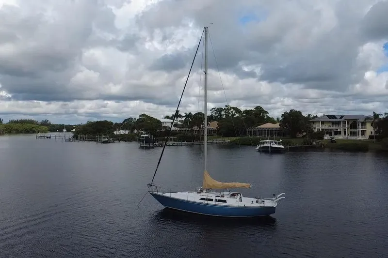 Slide: The Image of 1980 C&C Landfall 38 sailboat anchored on a calm river under cloudy skies. - 59