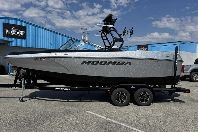 The Image of 2023 Moomba Max boat on trailer at dealership, under clear sky. - 1