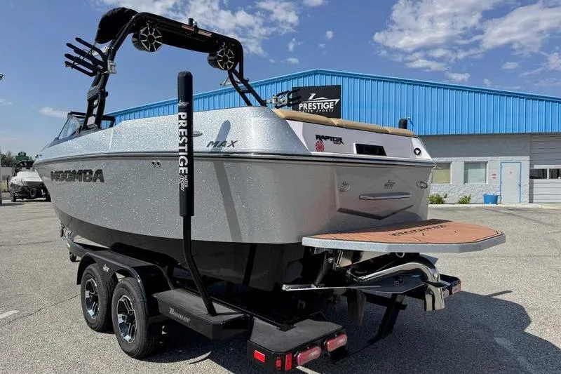 Slide: The Image of 2023 Moomba Max boat on trailer, parked outside a blue building under a clear sky. - 5