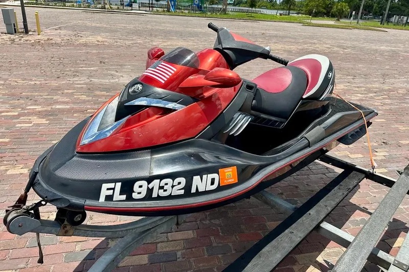 Slide: The Image of 2006 Sea-Doo RXT jet ski on trailer, red and black design, parked on brick pavement. - 4