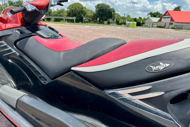 Slide: The Image of 2006 Sea-Doo RXT jet ski with red and black seat, parked outdoors. - 9