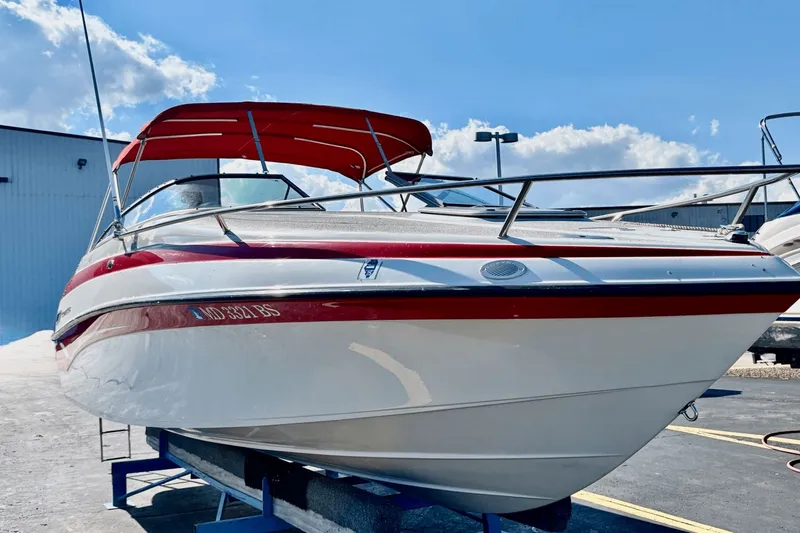 The Image of 2002 Crownline 215 CCR boat with red canopy, docked under a clear blue sky. - 0
