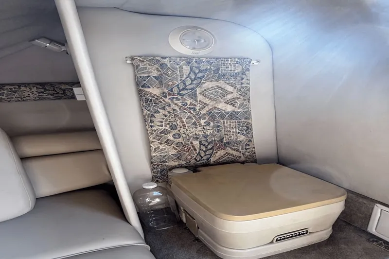 Slide: The Image of 2002 Crownline 215 CCR cabin interior with portable toilet and patterned curtain. - 9