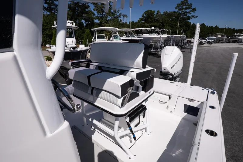 Slide: The Image of 2026 Blackfin 242 HB boat interior with seating and steering wheel, parked outdoors. - 19
