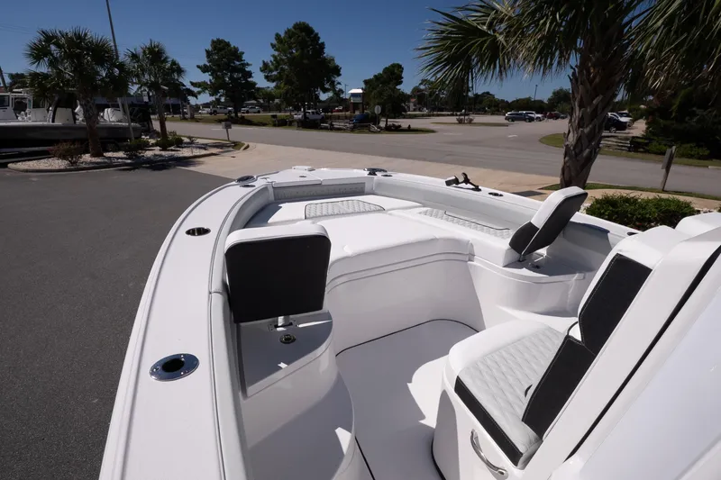 Slide: The Image of 2026 Blackfin 242 HB boat interior with white seating and palm trees in the background. - 22