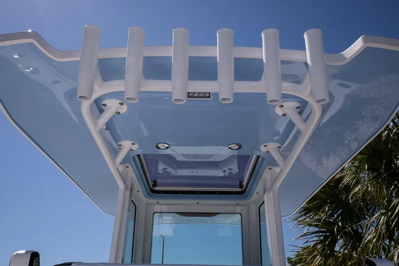 Slide: The Image of 2026 Blackfin 242 HB boat roof with rod holders under clear blue sky. - 25