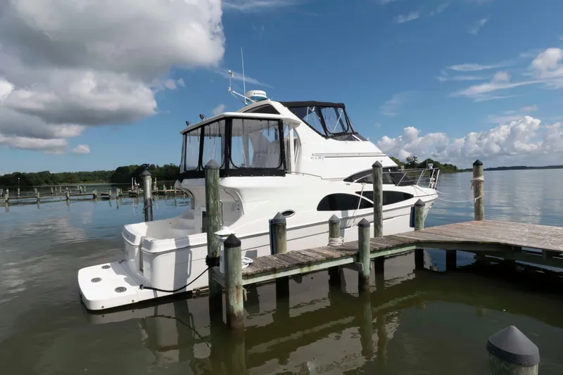 The Image of 2005 Carver 41 Cockpit Motor Yacht docked on a serene lake under a blue sky. - 0