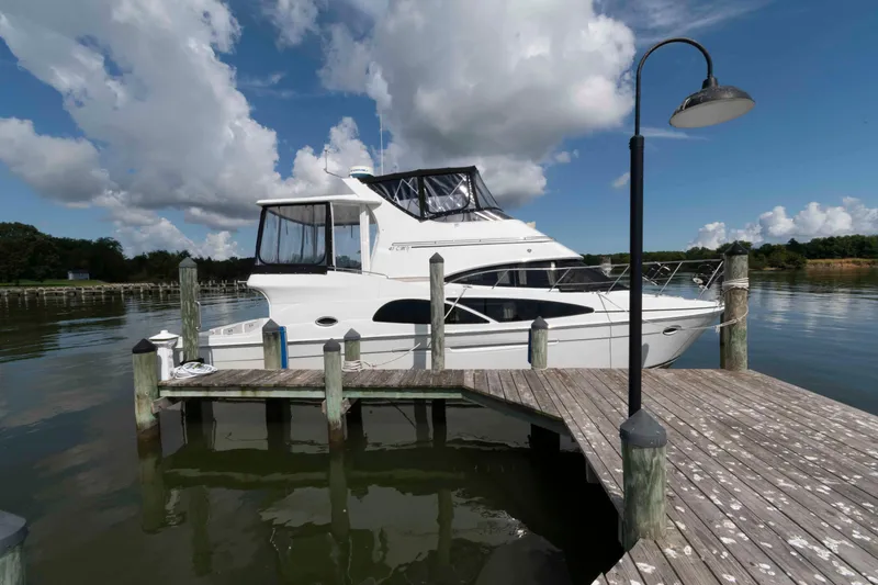 Slide: The Image of 2005 Carver 41 Cockpit Motor Yacht docked at a serene marina under a blue sky. - 1