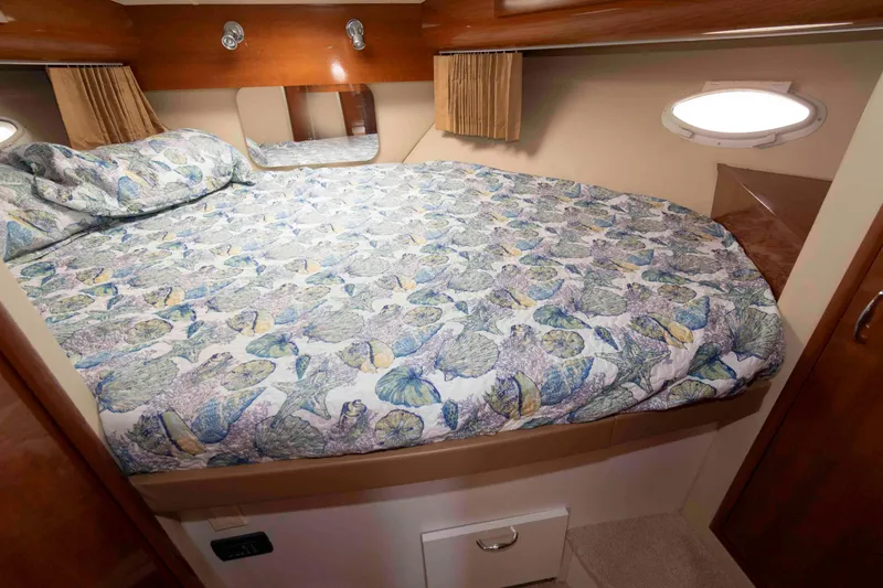 Slide: The Image of 2005 Carver 41 Cockpit Motor Yacht bedroom with fish-patterned bedding and wood accents. - 23