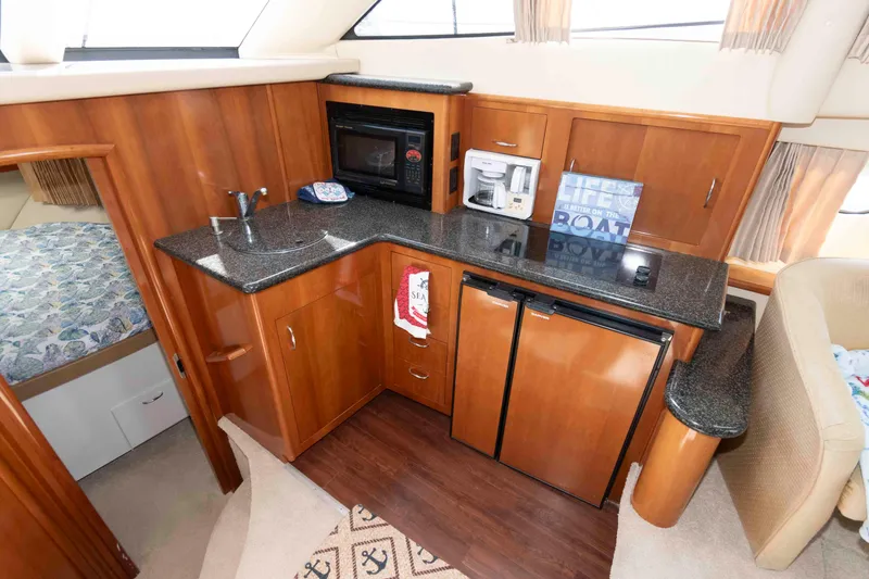Slide: The Image of 2005 Carver 41 Cockpit Motor Yacht interior kitchen with wood cabinetry and modern appliances. - 18