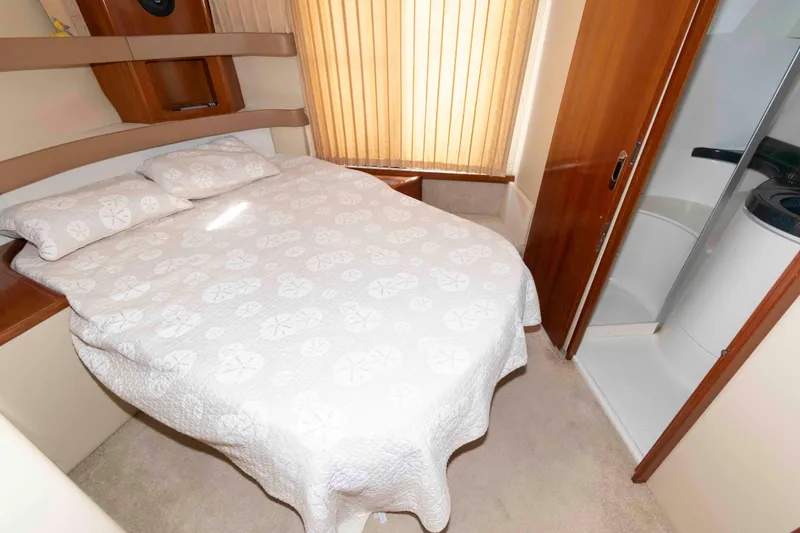 Slide: The Image of 2005 Carver 41 Cockpit Motor Yacht bedroom with cozy bed and adjacent bathroom. - 20