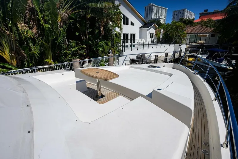 Slide: The Image of Front deck of a 2014 Hampton Fly yacht with a wooden table, docked near lush greenery. - 3