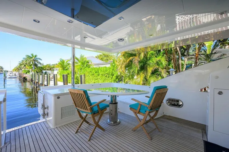 Slide: The Image of Luxurious 2014 Hampton Fly yacht deck with seating, overlooking serene waterfront and lush greenery. - 5