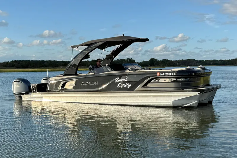 The Image of 2025 Avalon Excalibur Quad Lounge Windshield boat on calm water, side view. - 0