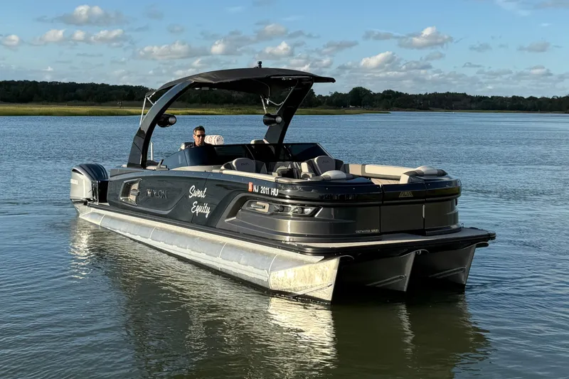 Slide: The Image of 2025 Avalon Excalibur Quad Lounge Windshield pontoon boat on a serene lake. - 10