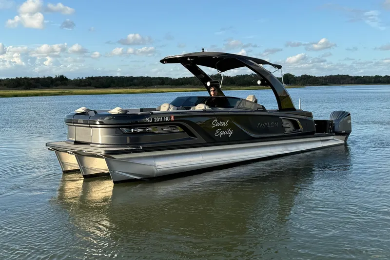 Slide: The Image of 2025 Avalon Excalibur Quad Lounge Windshield pontoon boat on a serene lake. - 11