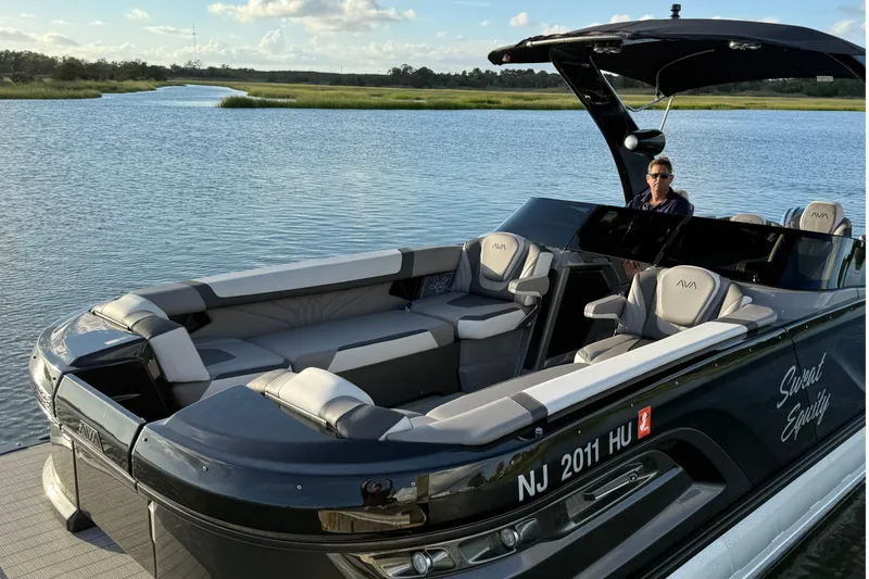 Slide: The Image of 2025 Avalon Excalibur Quad Lounge Windshield boat on serene water with luxury seating. - 13