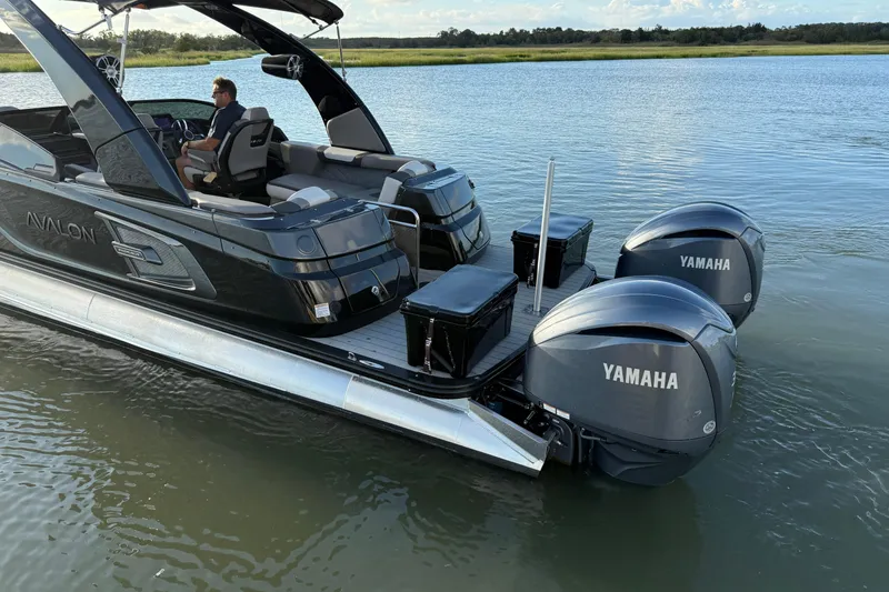Slide: The Image of 2025 Avalon Excalibur Quad Lounge Windshield boat with Yamaha engines on a serene lake. - 15