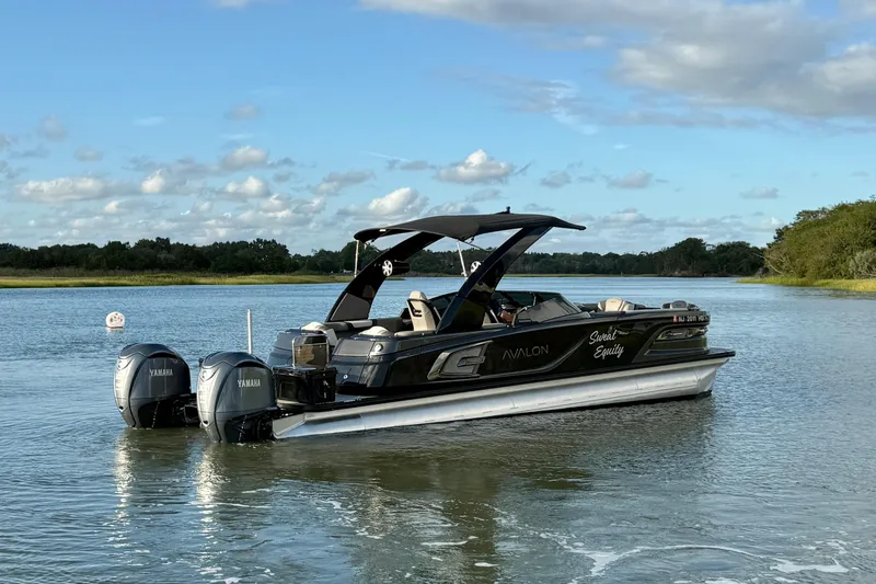 Slide: The Image of 2025 Avalon Excalibur Quad Lounge Windshield boat on a serene lake. - 7