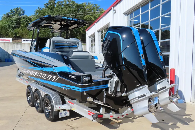 Slide: The Image of 2026 Sunsation 32 CCX boat with dual engines on a trailer, parked outside a building. - 4