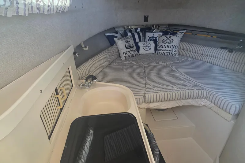 Slide: The Image of 1990 Grady-White Marlin 280 cabin interior with striped bedding and nautical-themed pillows. - 23