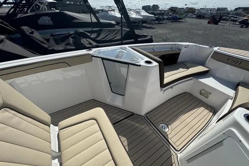 Slide: The Image of 2026 Yamaha Boats 255 FSH Sport H interior with beige seating and deck view. - 14